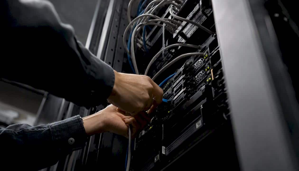 Sécurisation des données : guide pratique pour décideurs 1 Des mains connectent un câble réseau à une baie de serveurs.