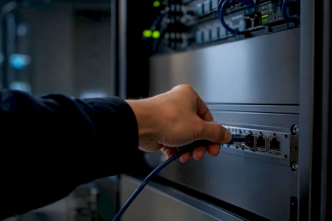 Main en train de configurer un câble réseau pour l'automatisation des données